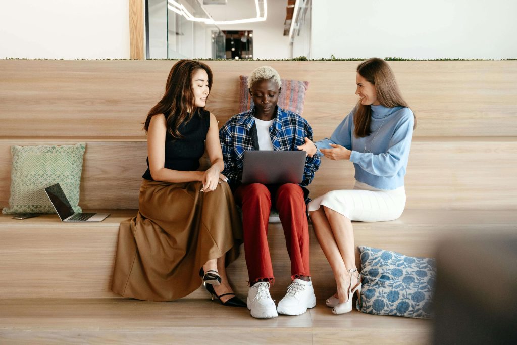 A diverse group of women working remotely on laptops in a collaborative, inclusive space, representing remote work gender inclusivity in purpose-driven careers.