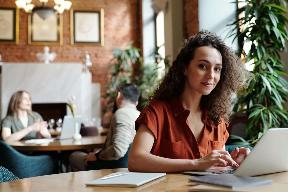 A woman working remotely on her laptop in a bright, modern space, representing remote work gender inclusivity in purpose-driven careers.